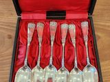 six silver spoons in a red box on a wooden table