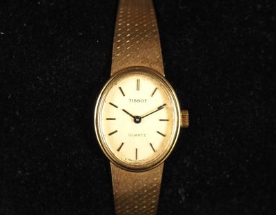 une image représentant une montre-bracelet dorée posée sur une surface noire