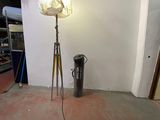 a lamp that is on a tripod next to a trash can