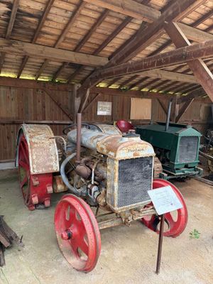 un vieux tracteur garé dans une grange au toit en bois