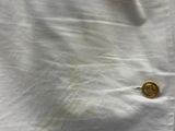 a white shirt with a gold button on it