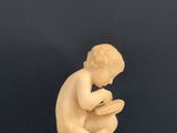 a small statue of a boy sitting on a stool reading a book