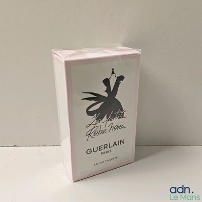 emballage d'un flacon de parfum Guerlain dans une boîte blanche posée sur une surface blanche