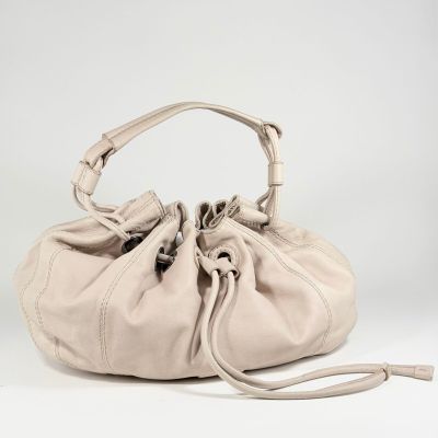 le grand sac beige est posé sur une surface blanche