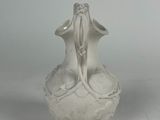 a white vase with a bird on it on a table