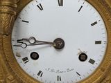 a gold clock with roman numerals on the face