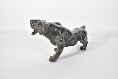 une petite statue représentant un chien posée sur une surface blanche