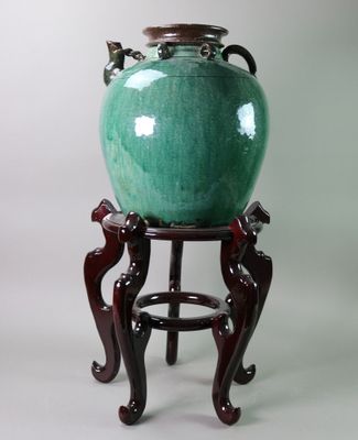 a green vase sitting on a stand on a white background