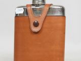 une gourde en cuir marron munie d'un couvercle en métal et d'un étui en cuir