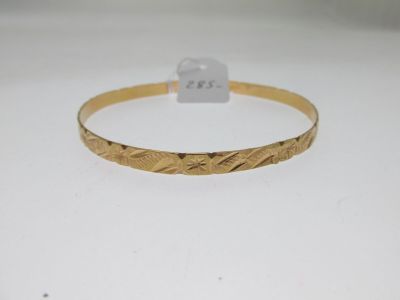 gros plan d'un bracelet en or sur une surface blanche