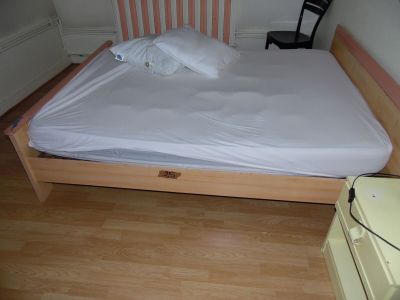 a bed with a wooden frame and a white sheet on it