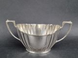 a silver plated bowl with handles on a black background