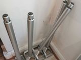 four metal pipes on the floor next to a wall