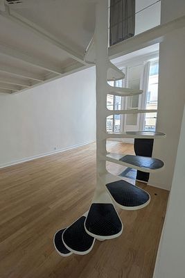 une pièce avec un parquet, des murs blancs et un escalier en colimaçon