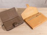two leather wallets sitting on top of a table next to each other