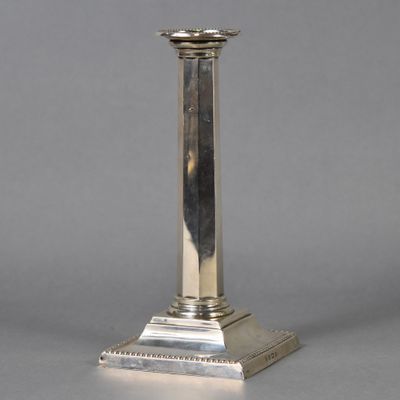 un bougeoir ancien en métal argenté posé sur une table