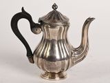 une théière ancienne en argent, dotée d'une anse noire sur un fond blanc