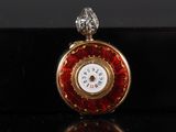 a close up of a red and gold pocket watch on a black surface