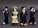 trois figurines représentant des personnes vêtues de bleu et de blanc, debout les unes à côté des autres