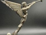 statue d'un ange tenant une trompette, posée sur un socle en marbre