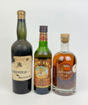 trois bouteilles d'alcool sont alignées sur une surface blanche