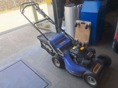 a blue lawn mower parked in front of a garage