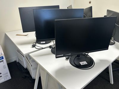 three computer monitors sitting on a desk in an office