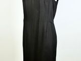 black sleeveless dress on a mannequin stand against a white wall