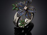 a close up of a flower ring with blue and green stones