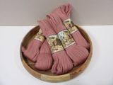 three skeins of pink yarn in a wooden bowl on a white surface