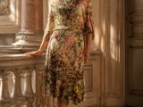 une femme debout sur un balcon, vêtue d'une robe