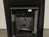 une photo d'un poêle noir dont la porte vitrée est cassée