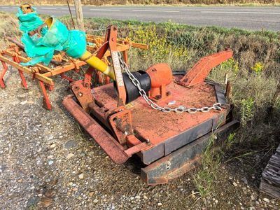 a tractor with a plow attached to it on the side of the road