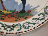 a decorative plate with a painting of a soldier holding a rifle