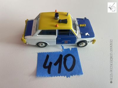 une petite voiture de police en jouet posée sur une table, à côté d'une feuille de papier bleue