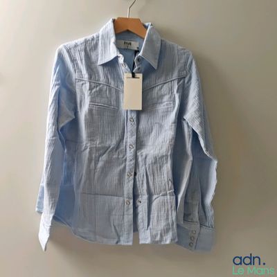 un gros plan d'une chemise suspendue à un cintre accroché au mur