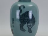un vase vert orné d'une image de chat