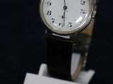 une montre posée sur un socle, sur une surface noire