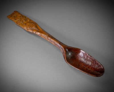 an old wooden spoon with a wooden handle on a gray background