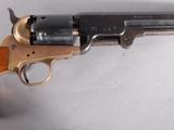 un vieux revolver avec une poignée en bois sur une surface blanche