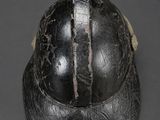 an old black helmet on a gray surface with a black background
