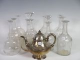 several glass bottles and a silver teapot sitting on a white surface