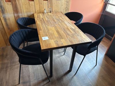 une table en bois entourée de quatre chaises noires