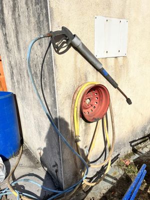 a hose that is attached to a wall next to a blue barrel