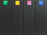 quatre livres noirs ornés de carrés colorés sont alignés en rangée