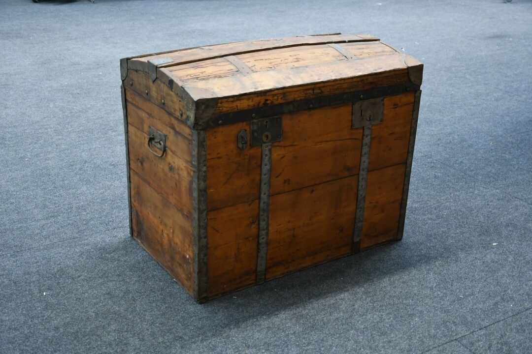 Grande malle à couvercle bombé en bois et renforts de métal.