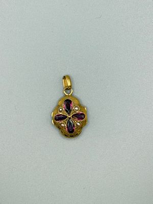 a close up of a gold pendant with a flower design on it