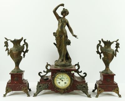 three bronze statues of a woman and two vases on a table