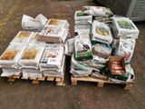 many bags of food sitting on pallets on the ground