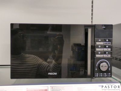 quelqu'un prend une photo d'un micro-ondes dans lequel on voit son reflet
